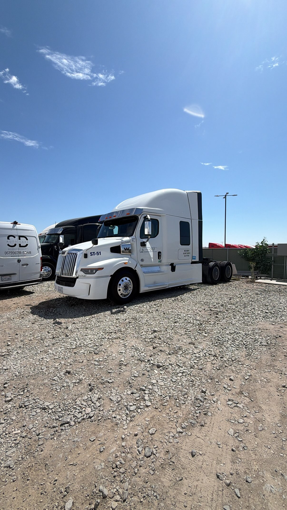 Washed white sleeper truck beside the San Diego Auto Care van