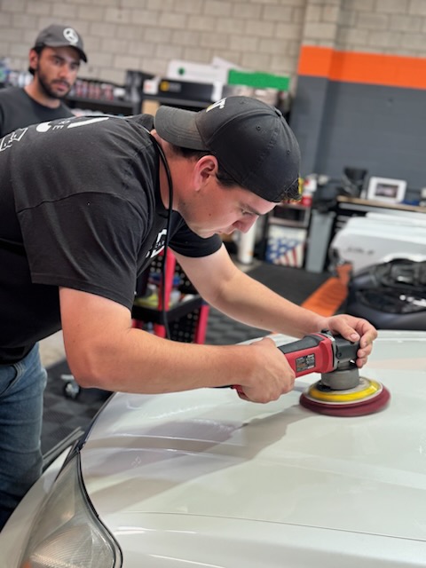 Technician machine polishing a vehicle hood