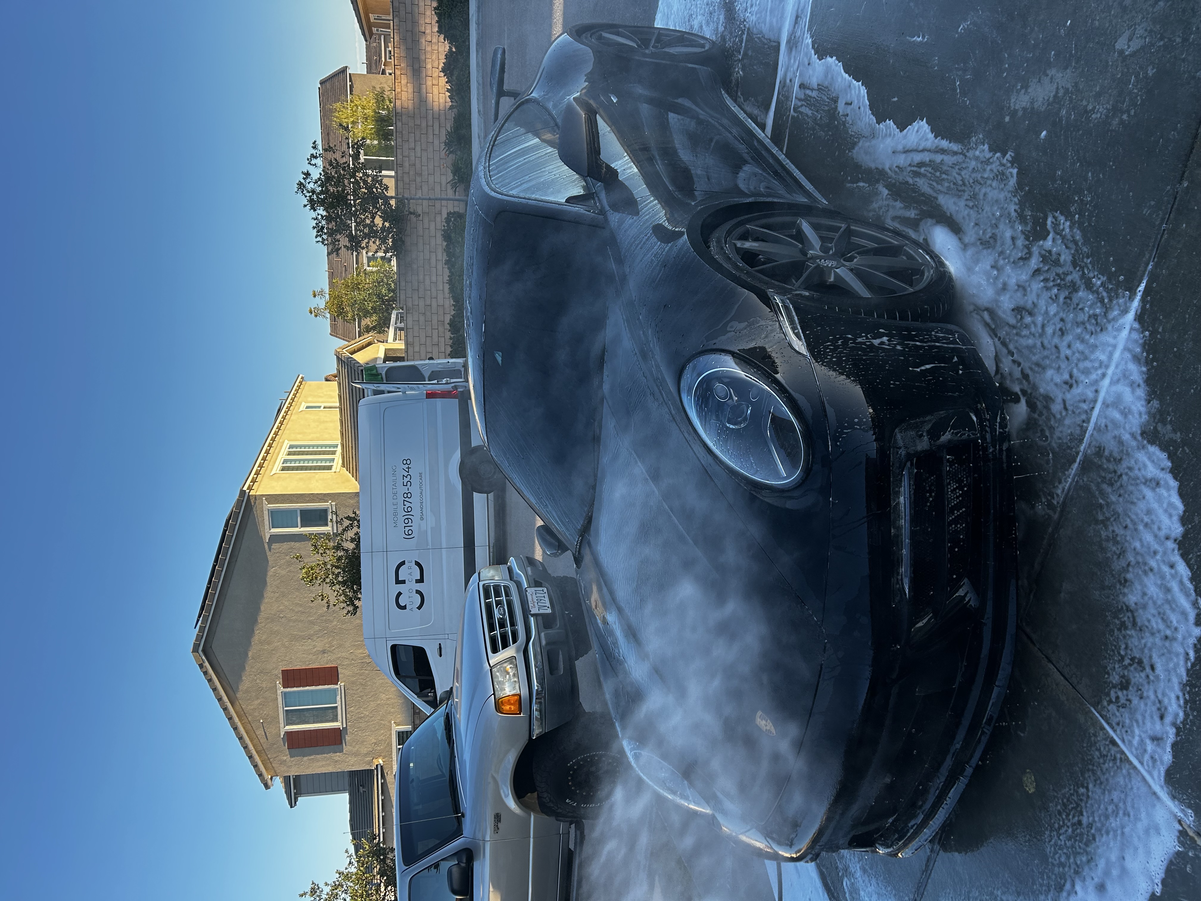 Dark sports car covered in wash foam during the wash