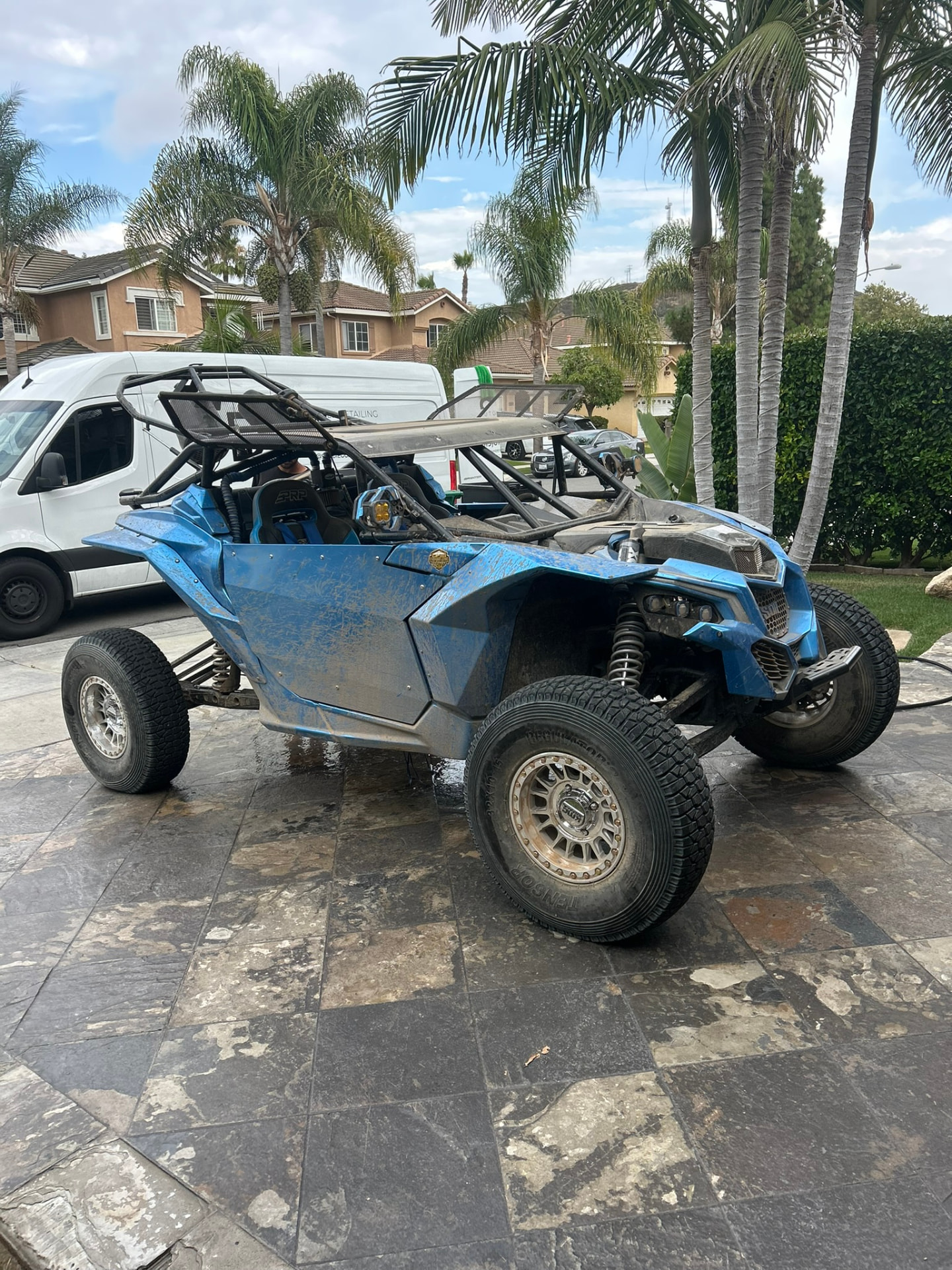Blue Can-Am X3 covered in trail dust before washing